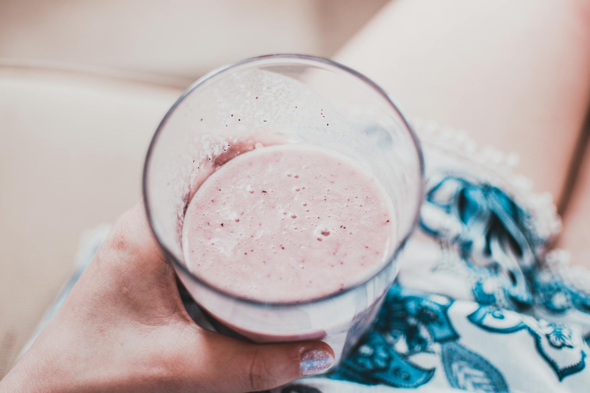 person holding clear drinking glass with fruit shake close up photo