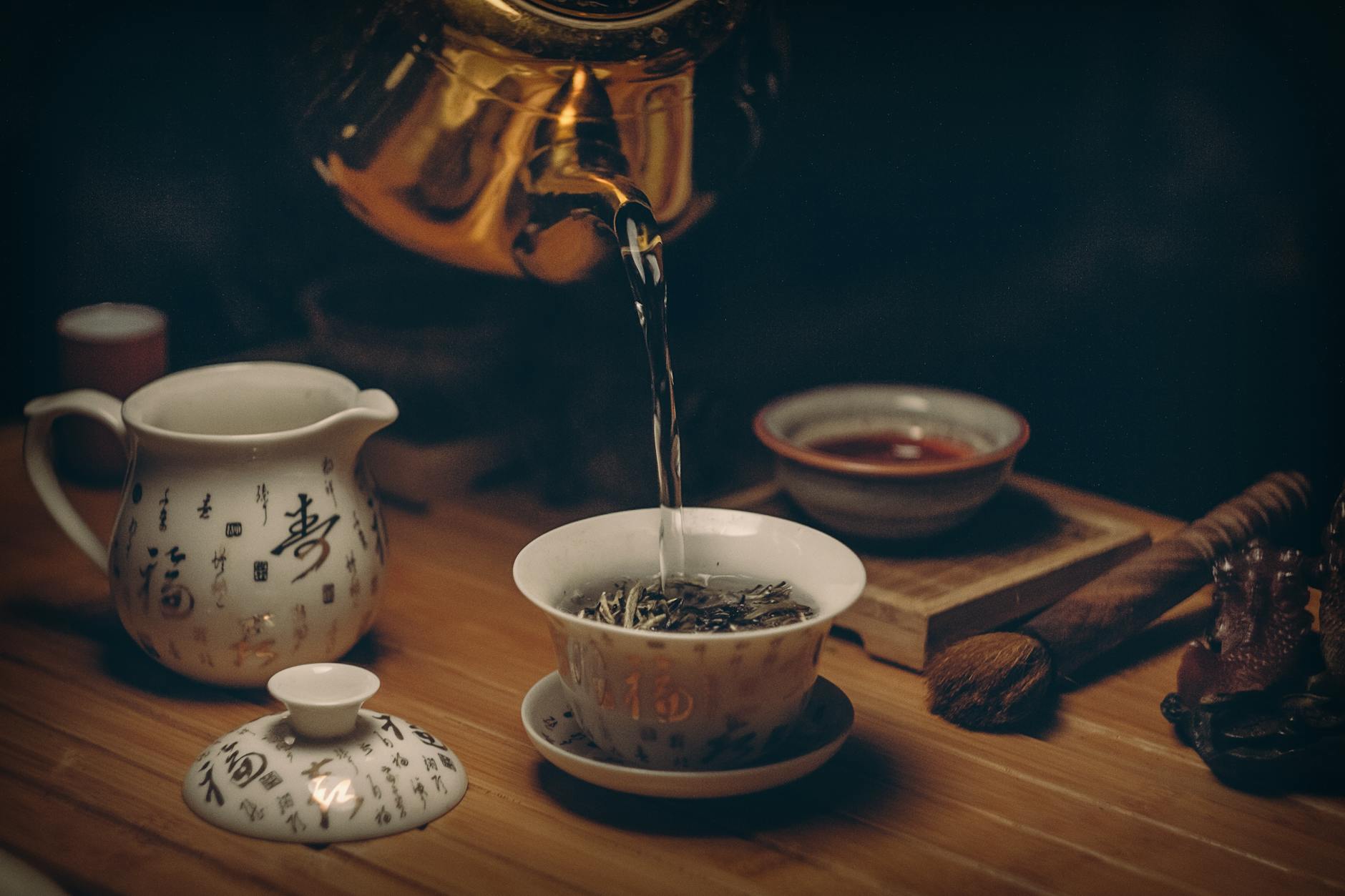 gold kettle pouring hot water on cup of tea