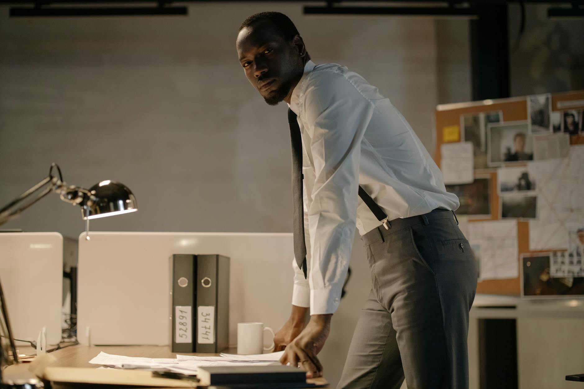 man wearing white long sleeves standing near work desk